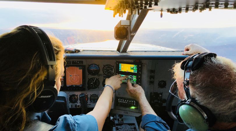 two people inside a small airplane working the controls from the pilot seats