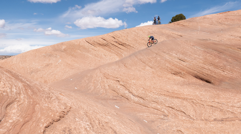 adventurous couple mountain biking on slickrock near moab on romantic couples getaway to utah