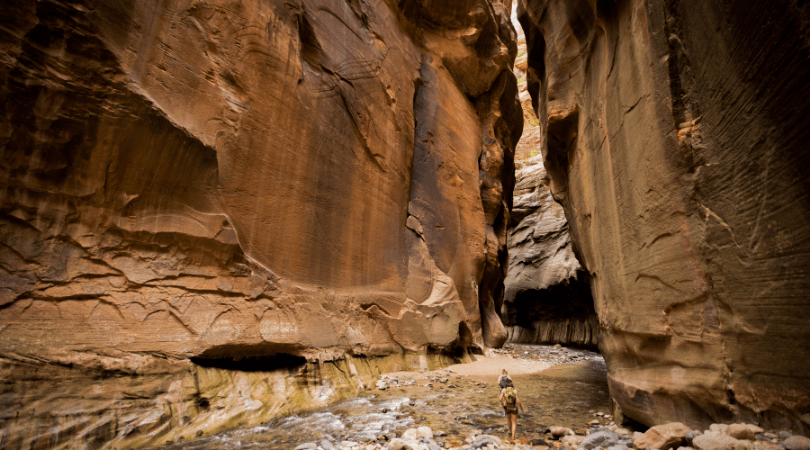 two people walking up narrows in Zion National Park during Mighty 5 trip