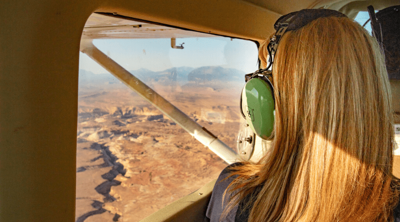 woman looking out airplane window on scenic air tour