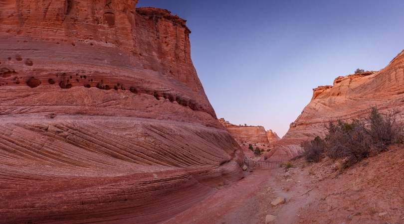 trail through red canyon walls in dusky light