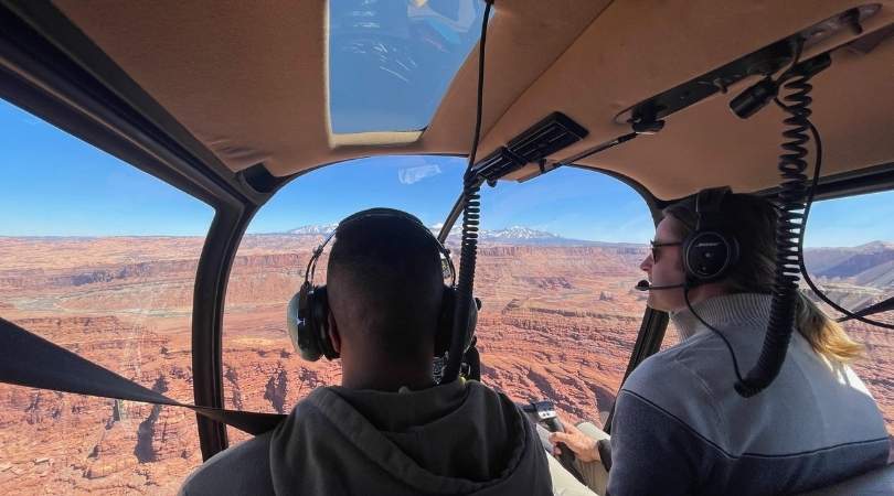 two people looking out at the desert through helicopter windows