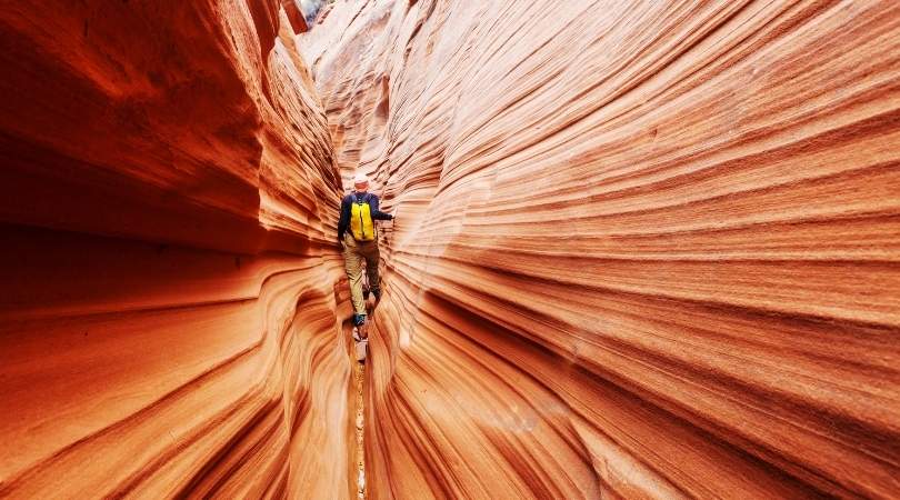 person canyoneering through a narrow slot canyon