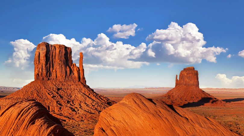 the mittens in monument valley with fluffy clouds and blue sky