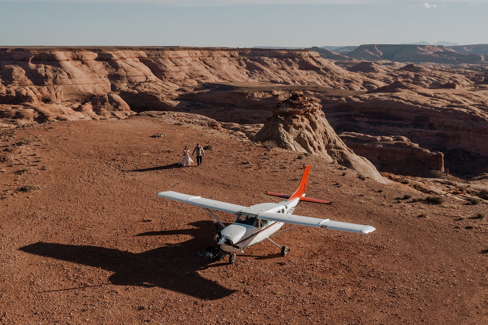 drone shot of couple walking near airplane during backcountry elopement