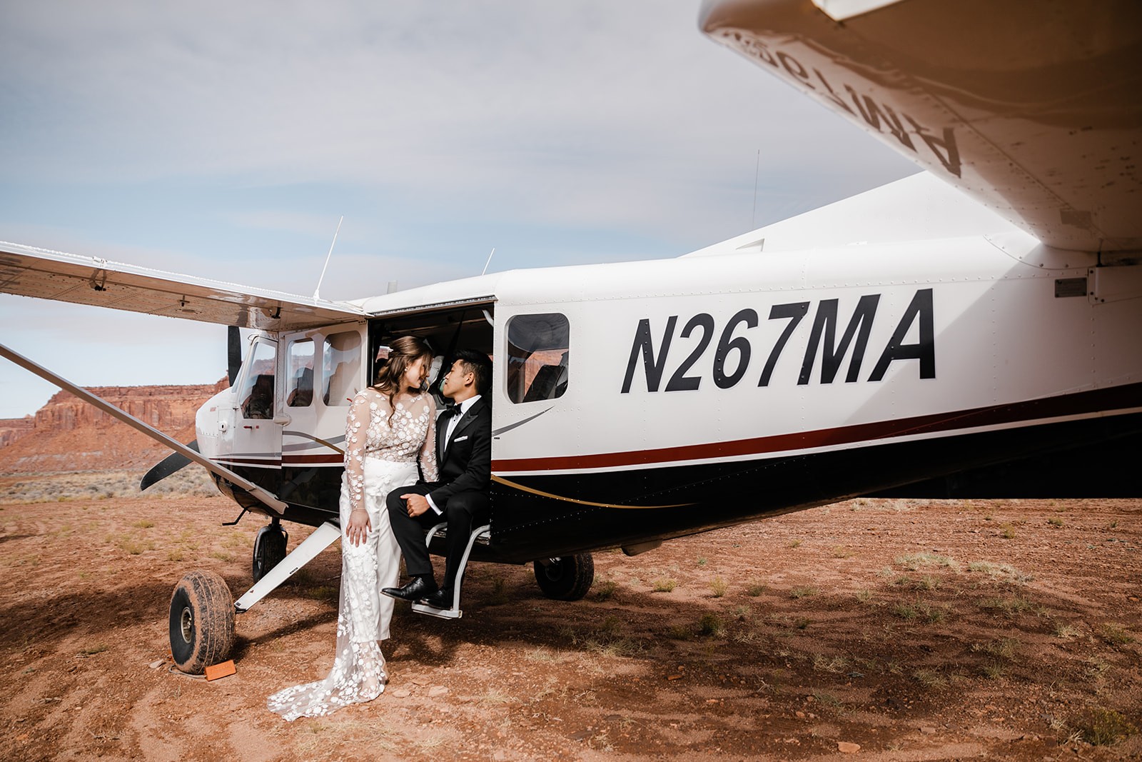 couple in wedding clothes sitting in an open door of landed airplane during their elopement