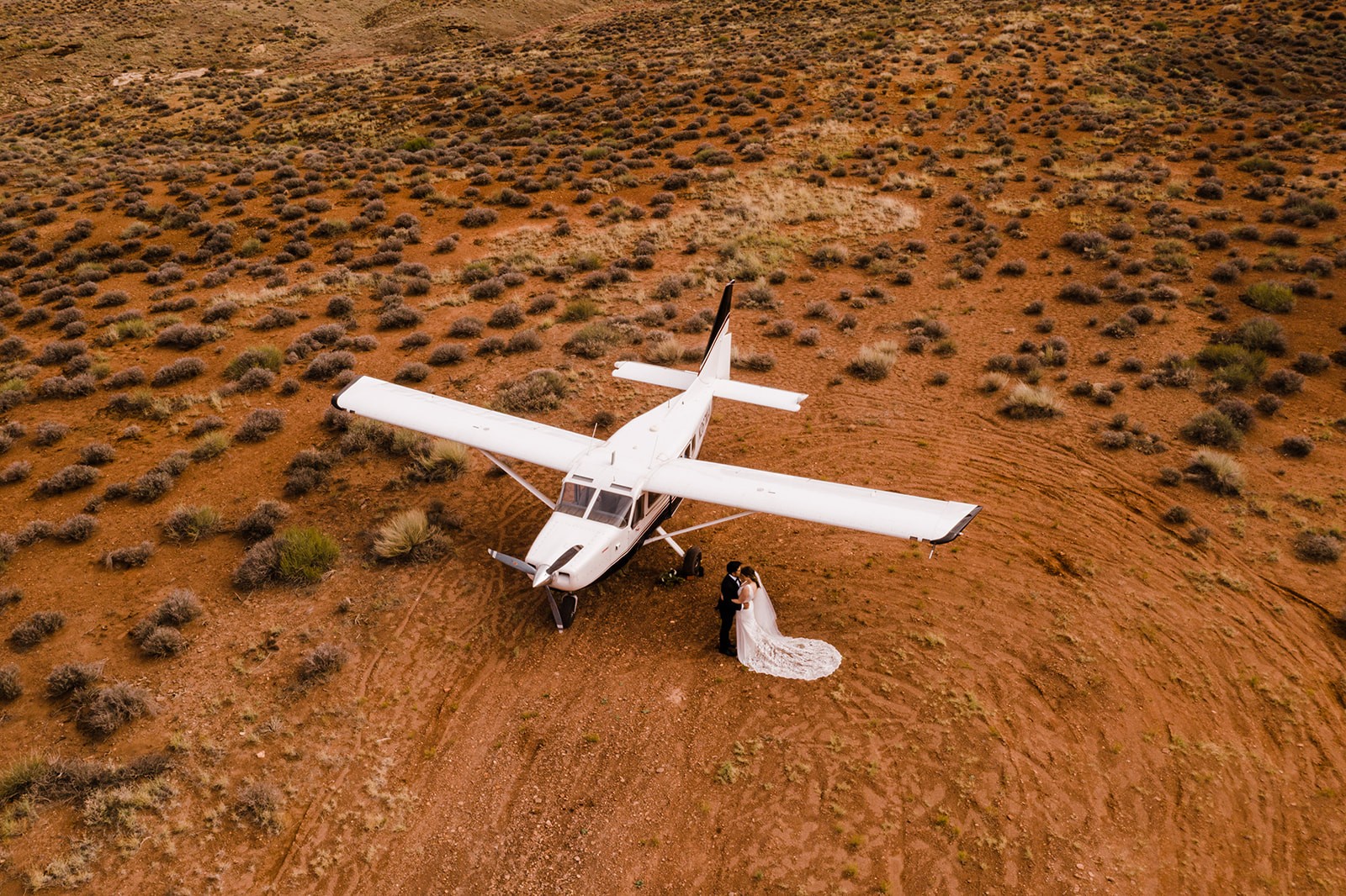 aerial drone shot of couple standing next to airplane in a backcountry elopement