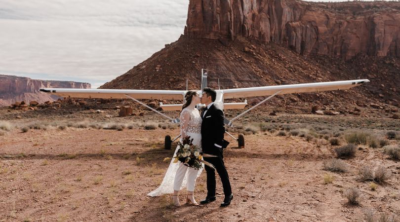 couple kissing in front of airplane during a backcountry elopement