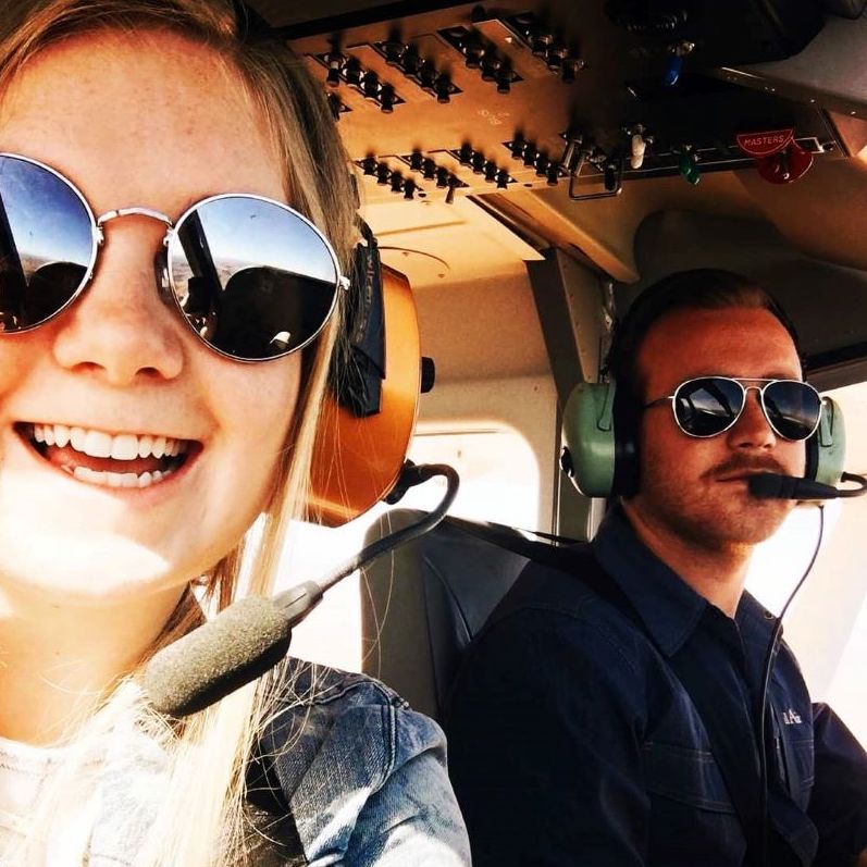 man and woman in sunglasses smiling in airplane