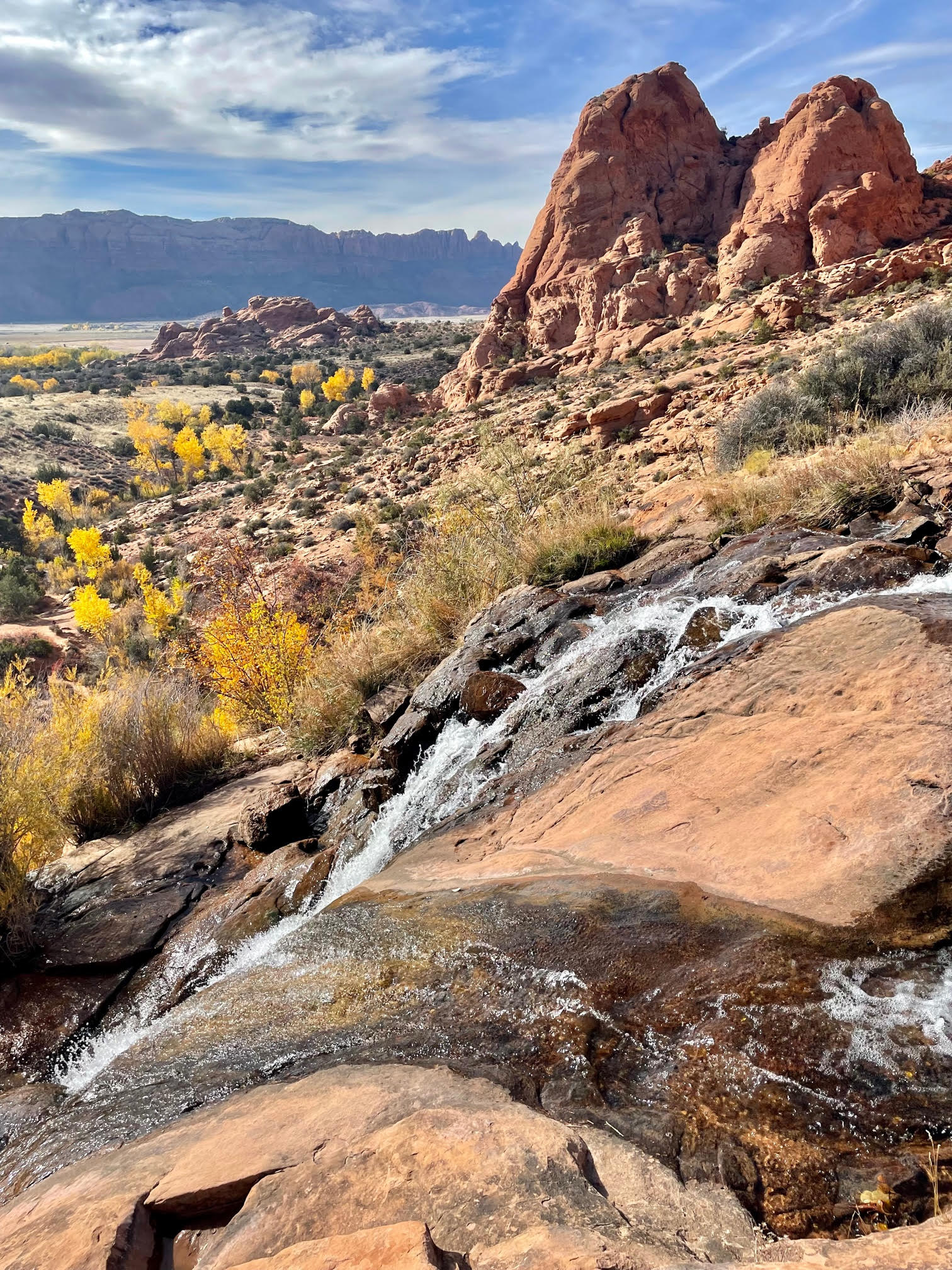 scene of a waterfall, autumn colors, and red rocks