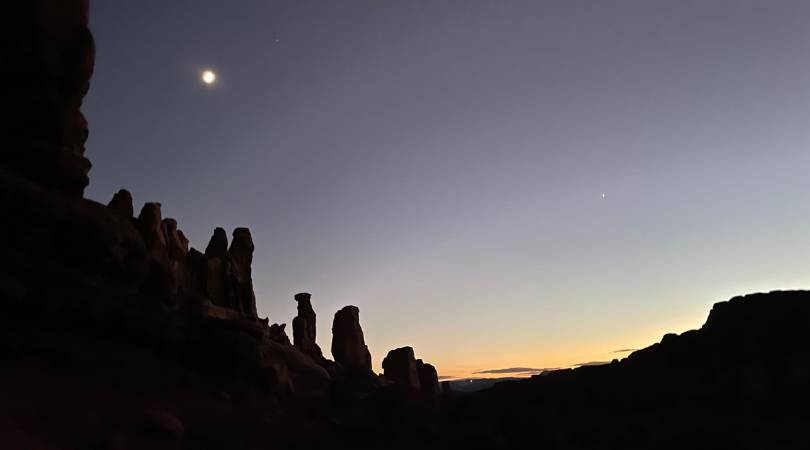 the moon above red rock towers at night