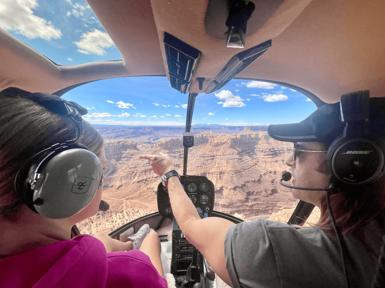 2 passengers in a helicopter looking over backcountry arches in moab and canyonlands