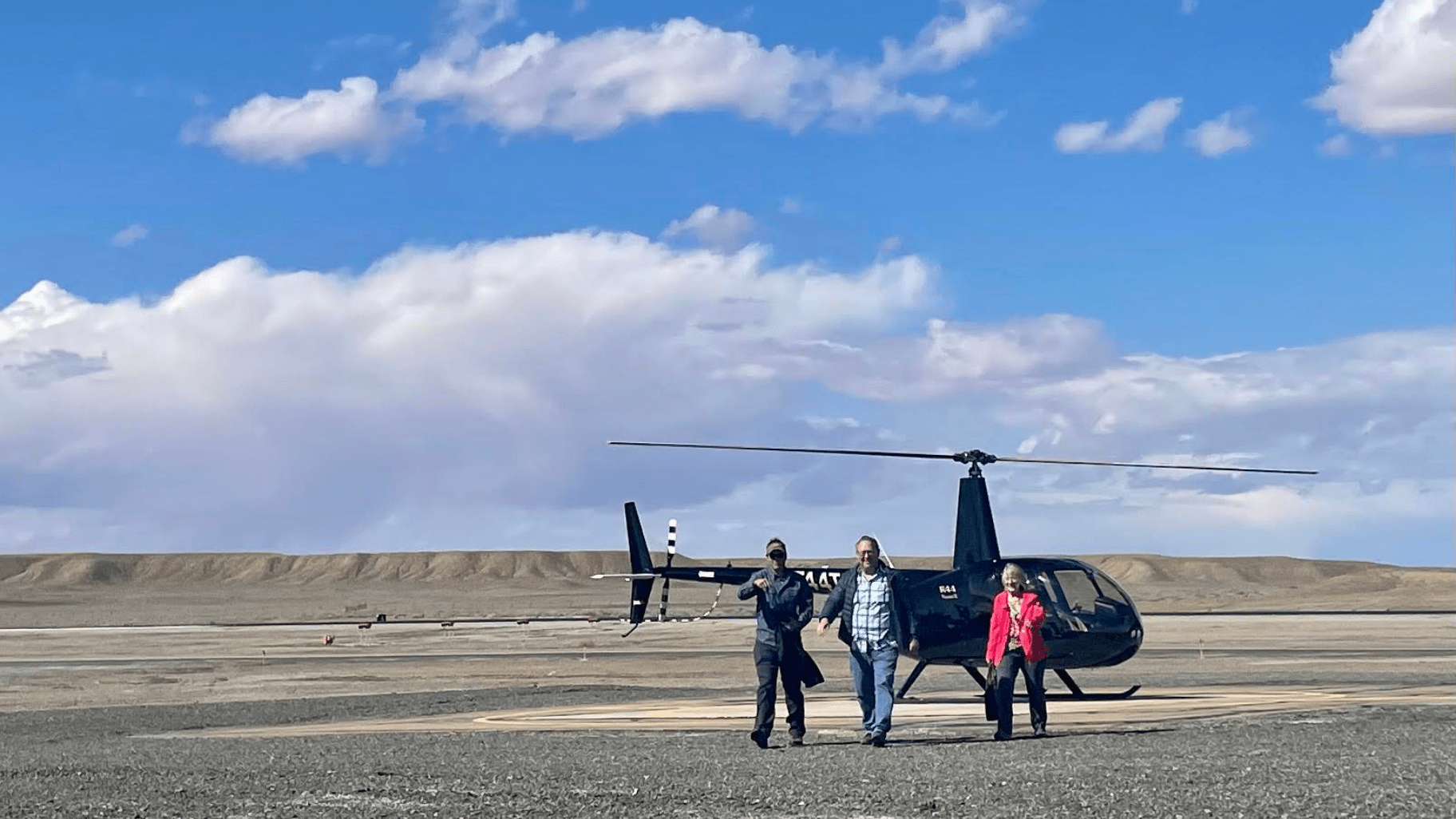 group of 3 walking away from a helicopter