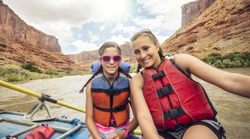 mom and daughter smiling on a river raft