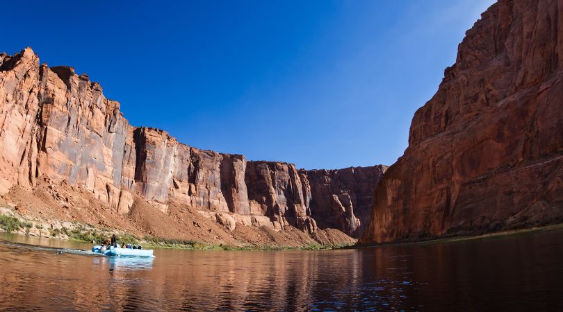 blue raft on a calm water with red canyon walls surrounding it