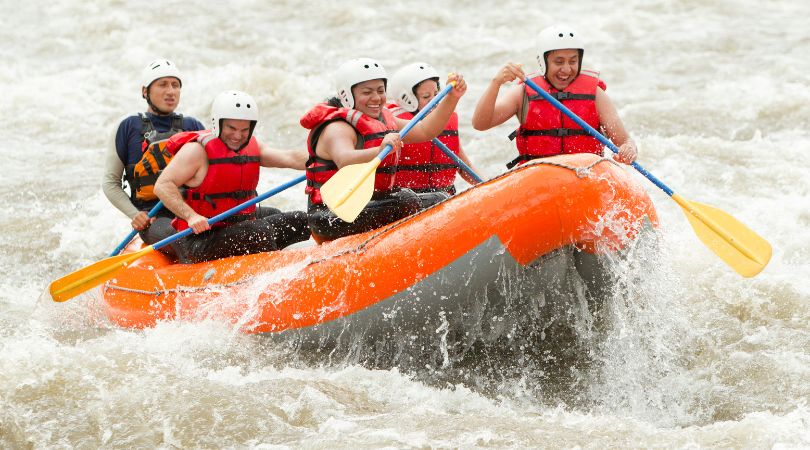 people on a white water raft with a guide going through rapids