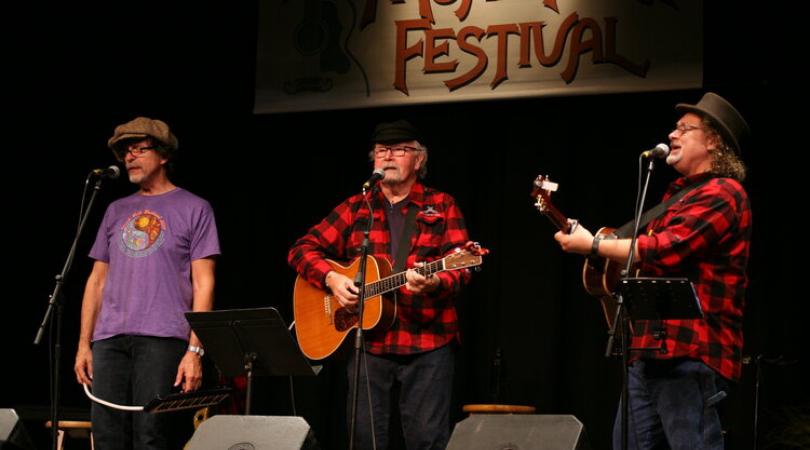 folk band of three performing at the moab folk festival in the fall