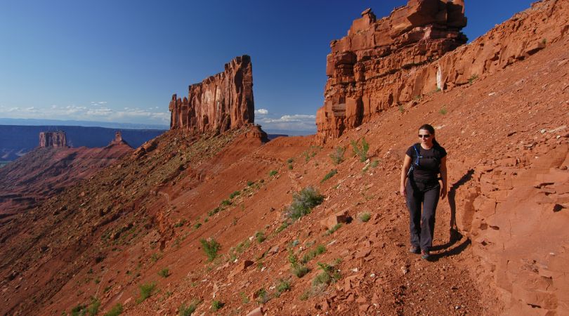 person hiking in moab with rock formations behind them