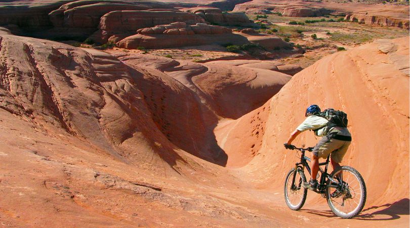 person mountain biking on slick rock in moab