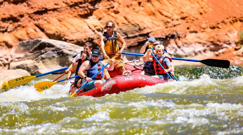 group of people on a red raft on the river in moab