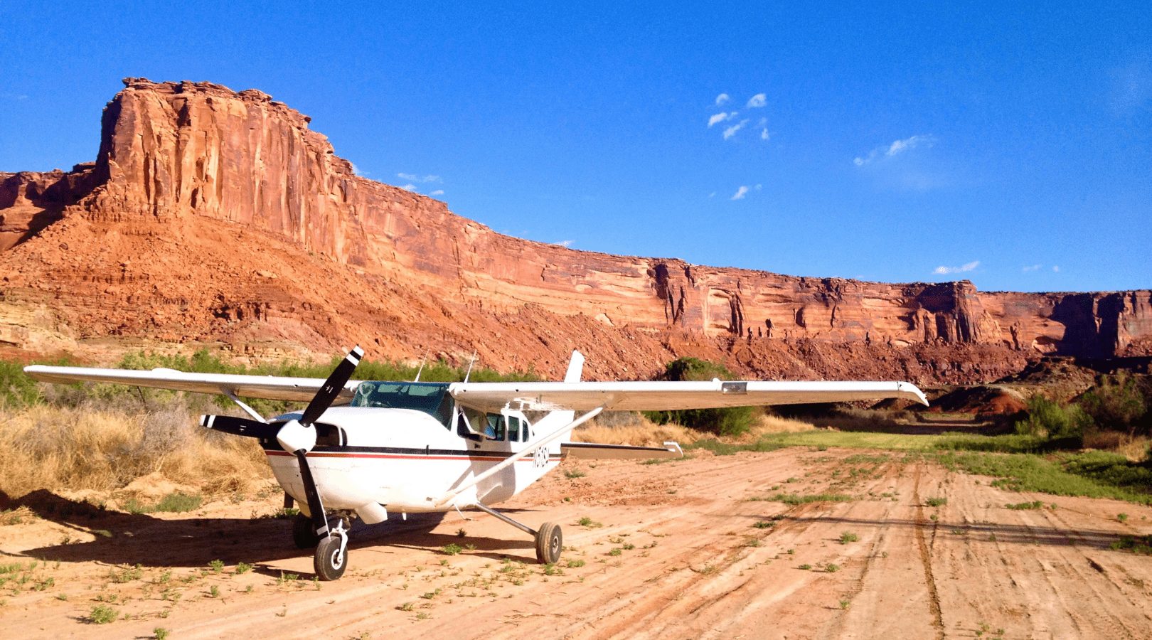 airplane at mineral bottom river take out with red rock canyon walls in the background