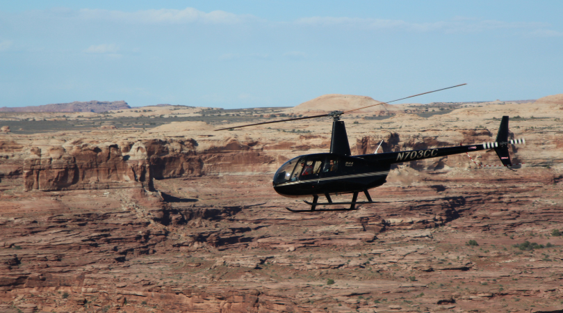 black helicopter flying over moab scenic landscape on a helicopter tour