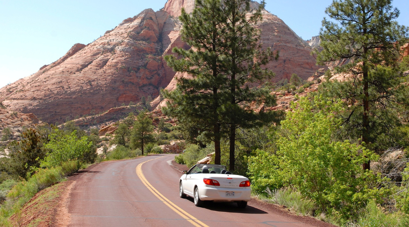 white car driving along a road in moab