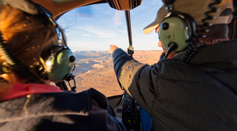 view out of the front of a helicopter with the pilot pointing out sites seen from a utah helicopter tour