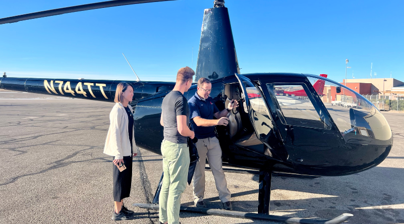 3 people gather outside a helicopter listening to a pre-flight briefing before their helicopter ride in moab